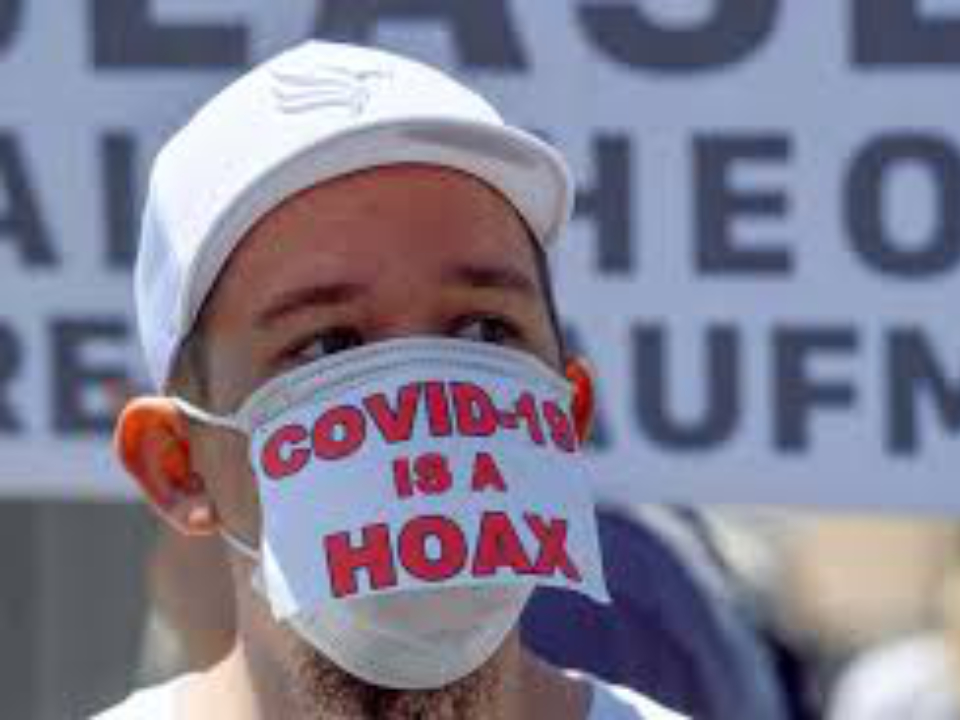 A man wearing a mask saying 'Covid19 is a hoax'