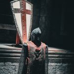 A knight is standing in front of a large shield
