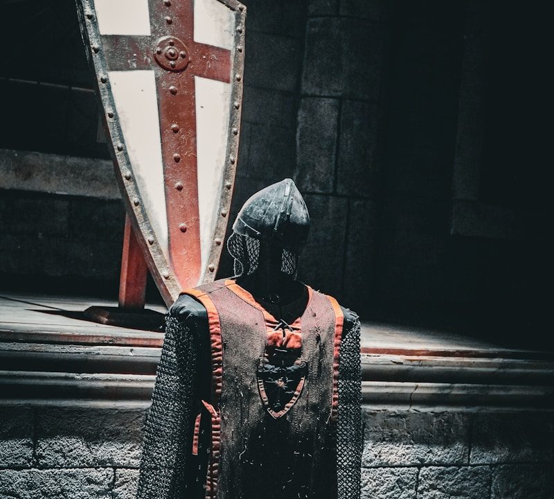 A knight is standing in front of a large shield