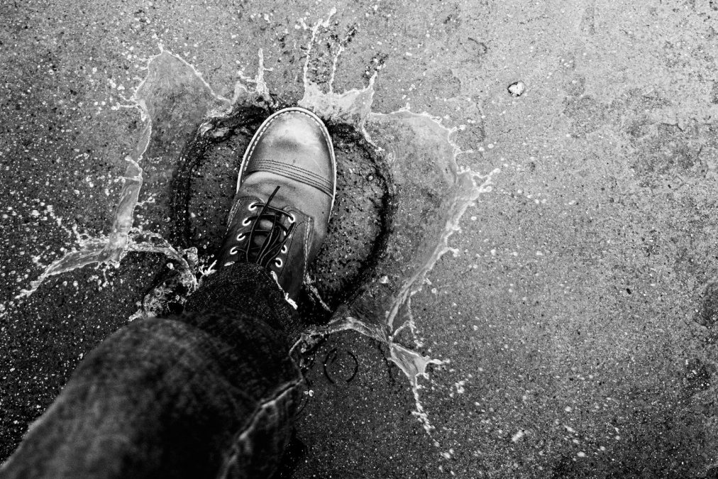 A boot splashes water on a textured surface