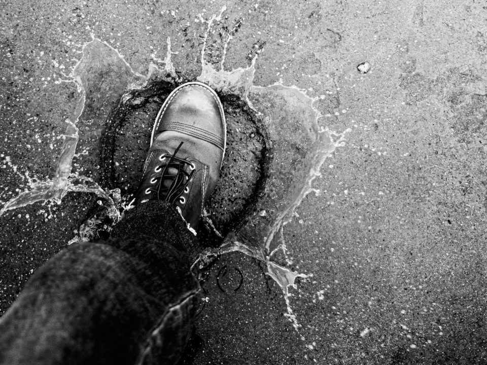 A boot splashes water on a textured surface